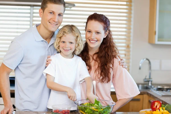 Smiling family preparing salad together — Stock Photo, Image