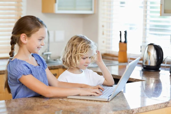 Siblings on the laptop in the kitchen — Stock Photo, Image
