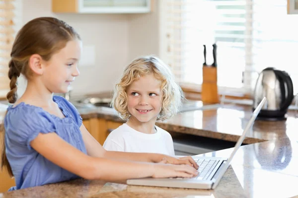 Siblings on the notebook in the kitchen — Stock Photo, Image
