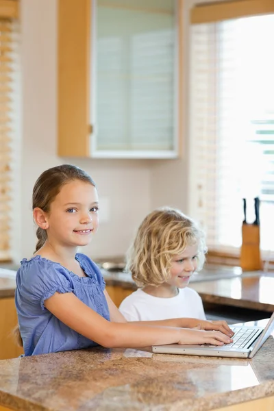 Brother and sister with laptop in the kitchen — Stock Photo, Image