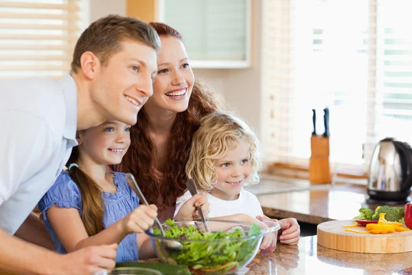 Famiglia insieme all'insalata in cucina — Foto Stock