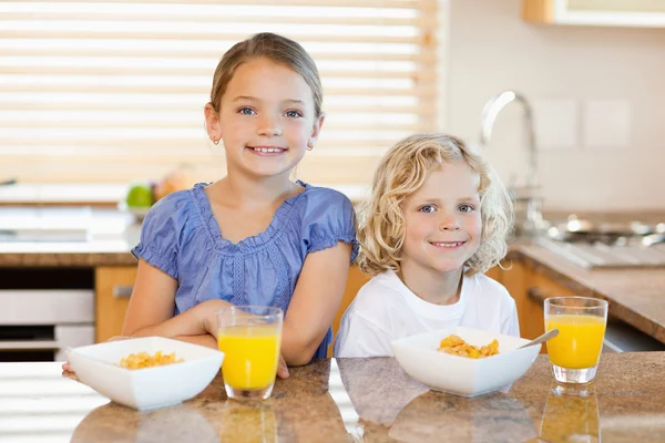 Geschwister mit Frühstück hinter der Küchentheke — Stockfoto