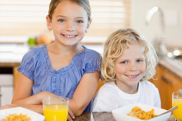 Brother and sister with breakfast in the kitchen — Stock Photo, Image