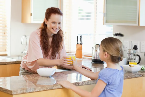 Mãe dando a sua filha suco de laranja — Fotografia de Stock