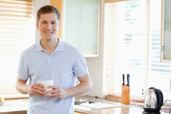 Человек с чашкой на кухне — стоковое фото