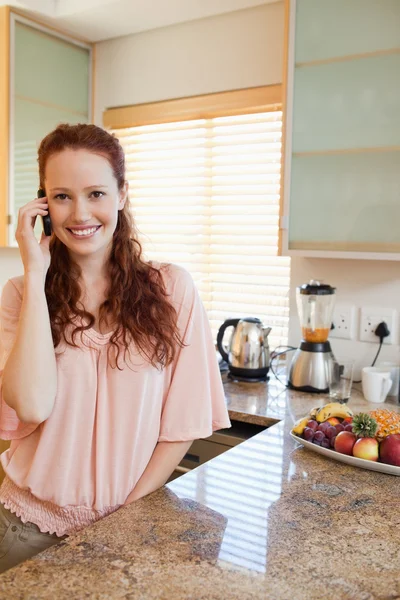 Mulher ao telefone ao lado do balcão da cozinha — Fotografia de Stock