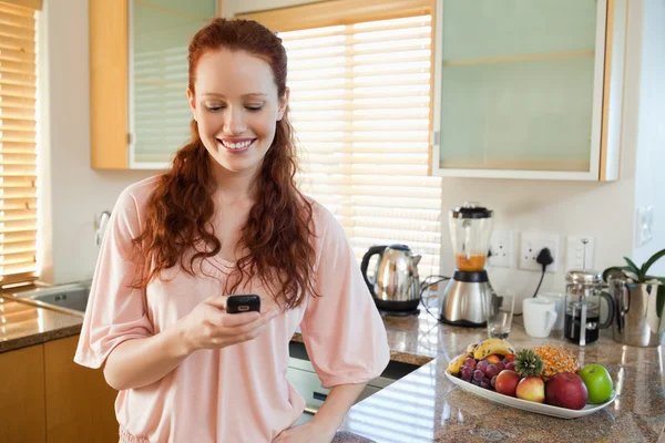 Woman in the kitchen writing text message — Stock Photo, Image