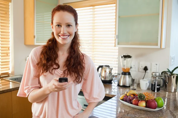 Donna che tiene il cellulare in cucina — Foto Stock