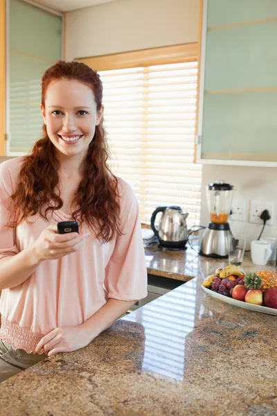 Žena v kuchyni se přes mobil — Stock fotografie