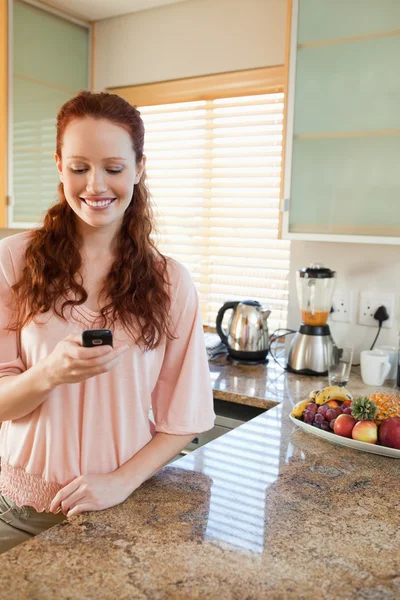 Žena psaní textové zprávy v kuchyni — Stock fotografie
