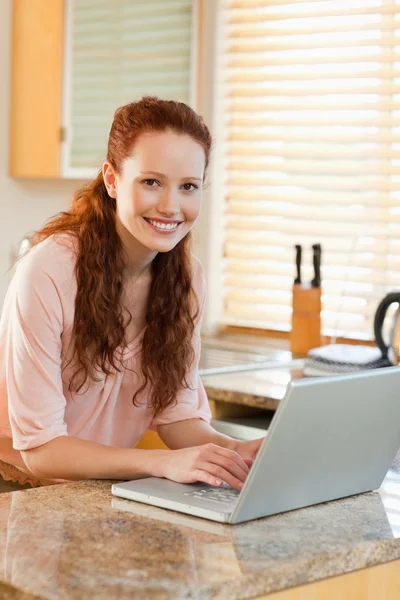 Vrouw met haar laptop naast het aanrecht — Stockfoto