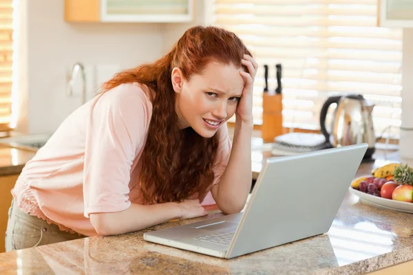 Mujer molesta por el ordenador portátil en la cocina —  Fotos de Stock