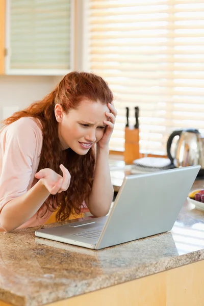 Woman looking annoyed at her laptop — Stock Photo, Image