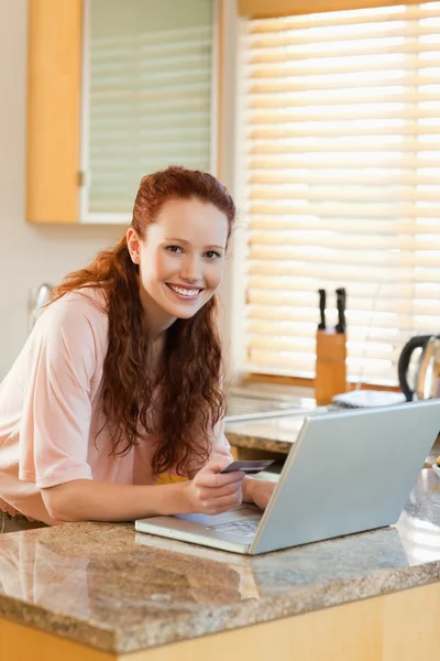 Lächelnde Frau in der Küche bucht Urlaub online — Stockfoto