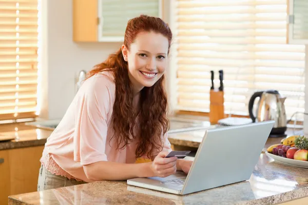 Woman booking flight online in the kitchen — Stock Photo, Image