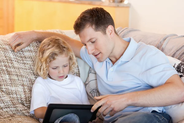 Padre e hijo usando la tableta en el sofá — Foto de Stock