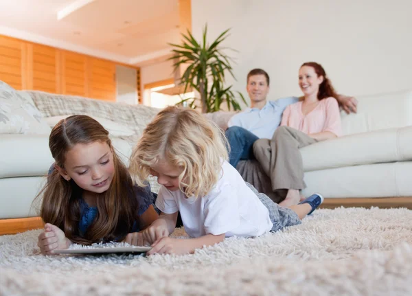 Dzieci za pomocą tabletki na dywanie — Zdjęcie stockowe