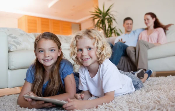 Broers en zussen op het tapijt met behulp van Tablet PC — Stockfoto