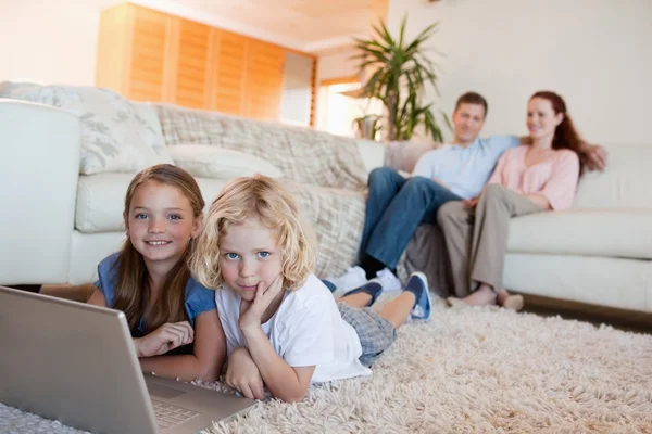 Broers en zussen met laptop op de verdieping — Stockfoto