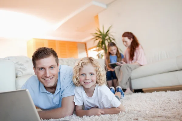Far och son använder internet i vardagsrummet — Stockfoto