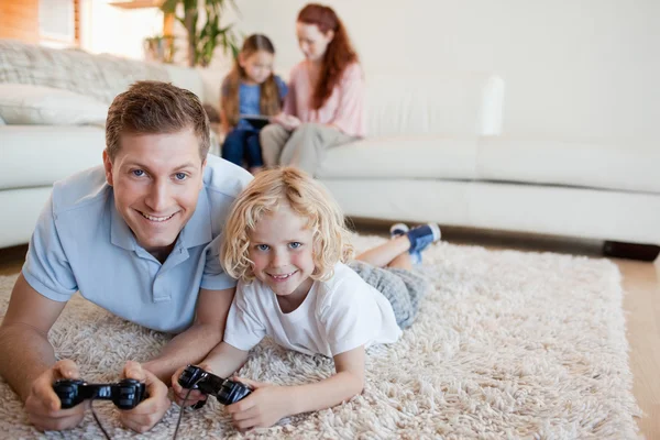 Far och son på golvet spelar TV-spel — Stockfoto