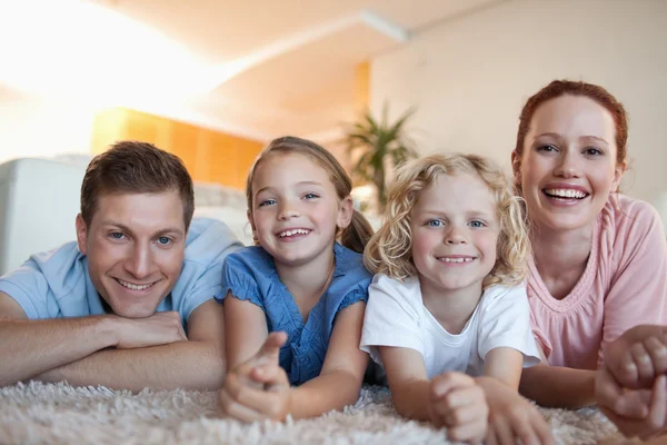 Veselý usměvavý rodina na koberec — Stock fotografie