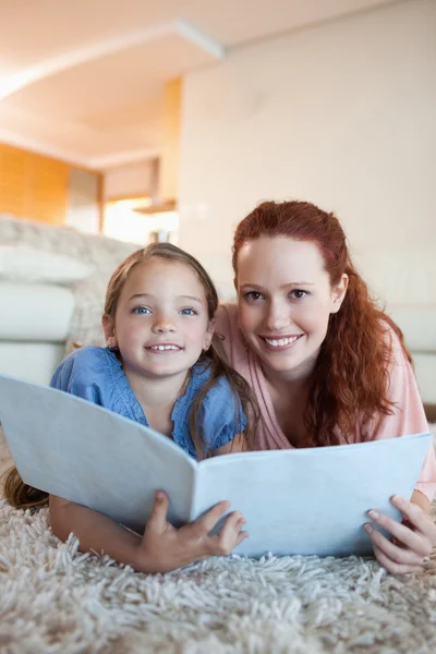 Mother and daughter with magazine on the the floor — Stock Photo, Image