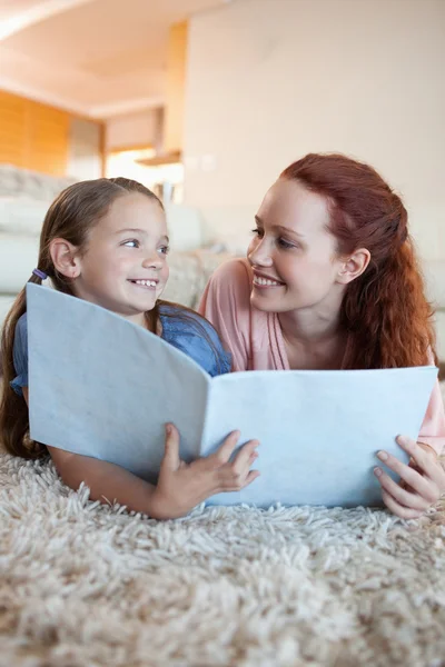 Mother and daughter on the floor looking at magazine — Stock Photo, Image