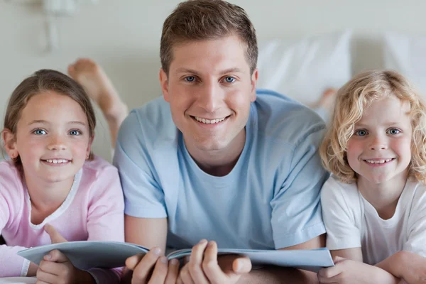 Sorrindo pai com seus filhos e uma revista — Fotografia de Stock