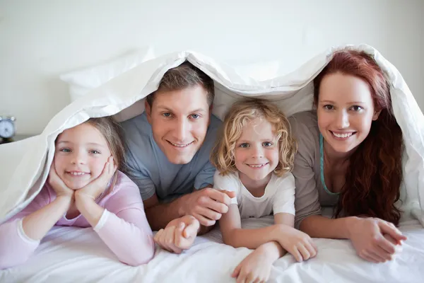 Família feliz sob tampa da cama — Fotografia de Stock