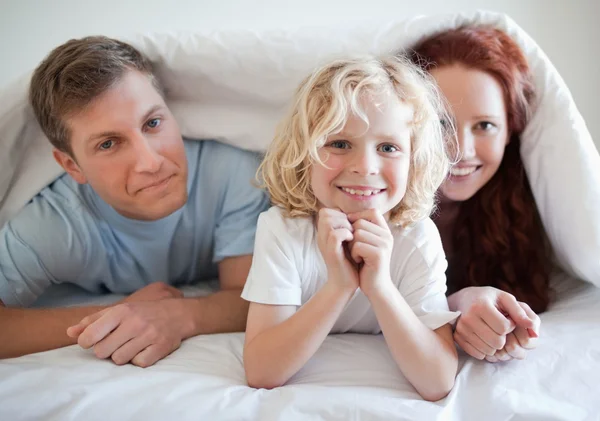 Хлопчик з батьками під прикриттям ліжка — стокове фото
