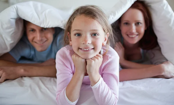 両親とベッドのカバーの下の女の子 — ストック写真