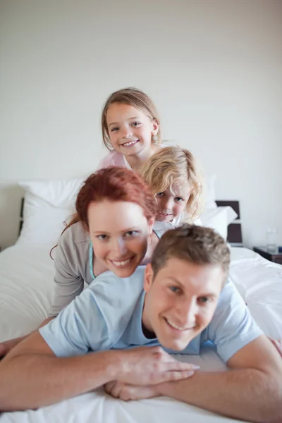 Família alegre deitada uma sobre a outra — Fotografia de Stock