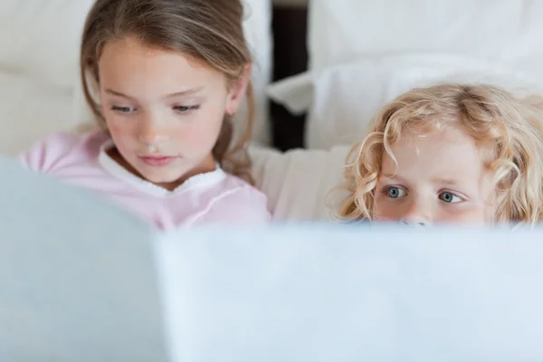 A lány bátyja olvasó egy ágy idő story — Stock Fotó