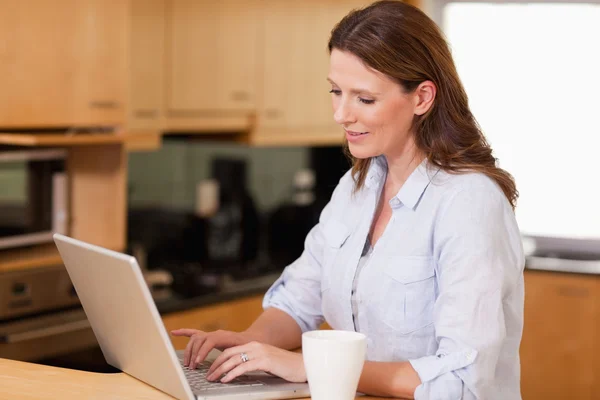 Vrouw in de keuken met behulp van haar laptop — Stockfoto