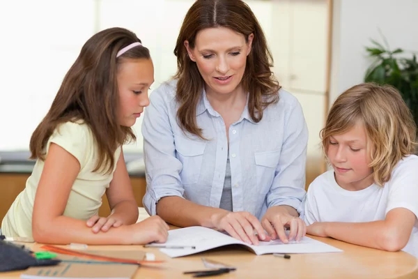 Frau hilft Kindern bei den Hausaufgaben — Stockfoto