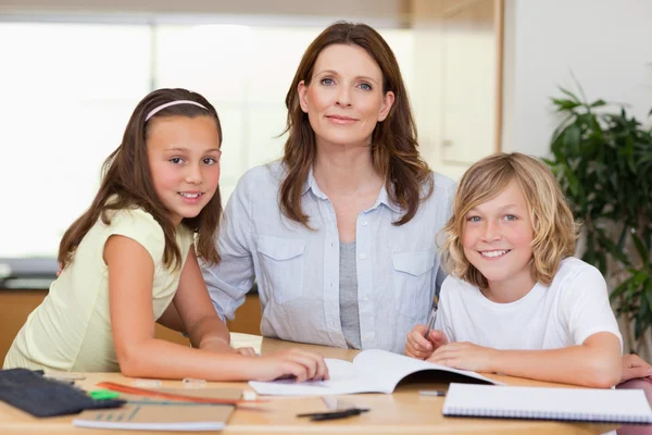 Donna aiutare i suoi figli con i compiti — Foto Stock