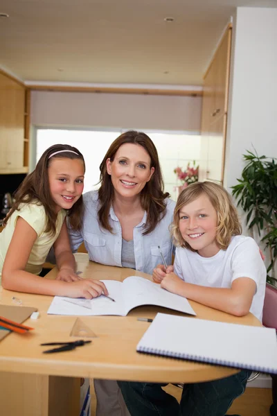 Сироти отримують допомогу з домашнім завданням від матері — стокове фото