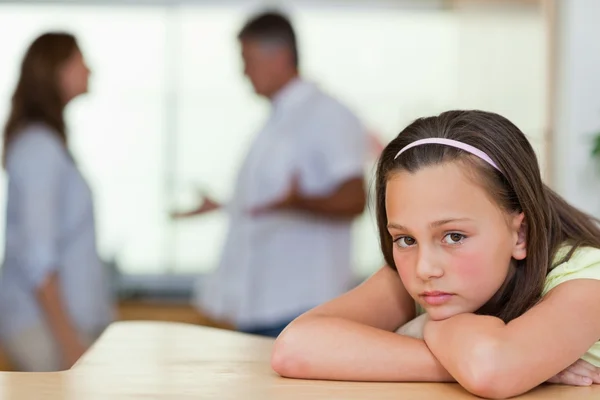 Sad girl with fighting parents behind her — Stock Photo, Image