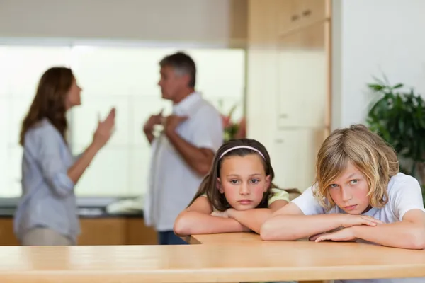 Triest kijken broers en zussen met ruzie ouders achter hen — Stockfoto