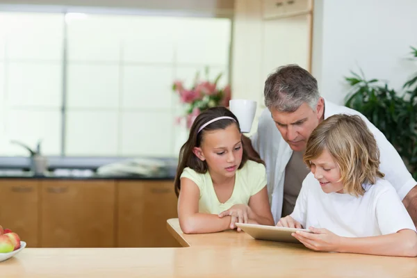 Man op zoek naar Tablet PC die zijn kinderen zijn met behulp van — Stockfoto