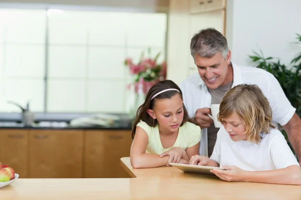 Vader met de kinderen en de Tablet PC in de keuken — Stockfoto