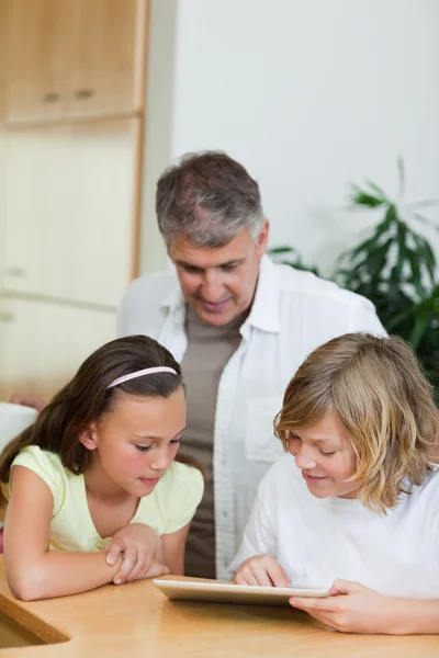 Boy with tablet showing things to sister and father — Stock Photo, Image