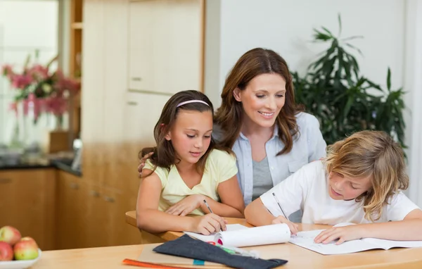 Moeder met een blik op kinderen huiswerk — Stockfoto