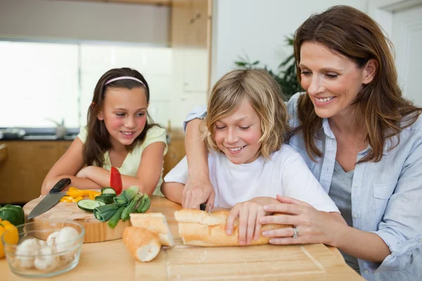 Mulher fazendo sanduíches com seus filhos — Fotografia de Stock