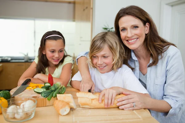 Moeder broodjes met haar kinderen maken — Stockfoto