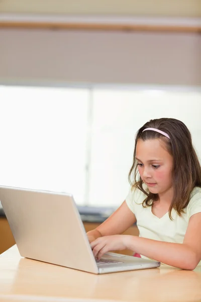 Menina digitando no laptop na cozinha — Fotografia de Stock