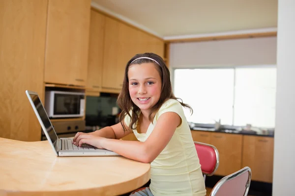 Girl with laptop at the kitchen table — Stock Photo, Image