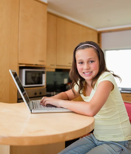 Meisje met haar laptop op de keukentafel — Stockfoto