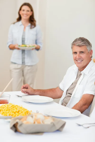 Man waiting for his wife to bring salad to the table — Stock Photo, Image